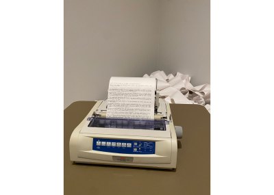 An old school printer at work, with an endless scroll behind it.